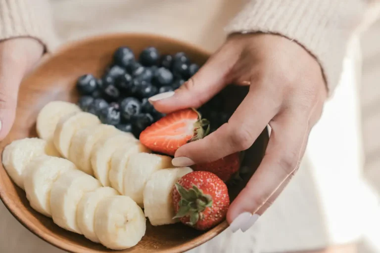Close up of a Person Holding a Wooden Plate with Fresh Fruit
